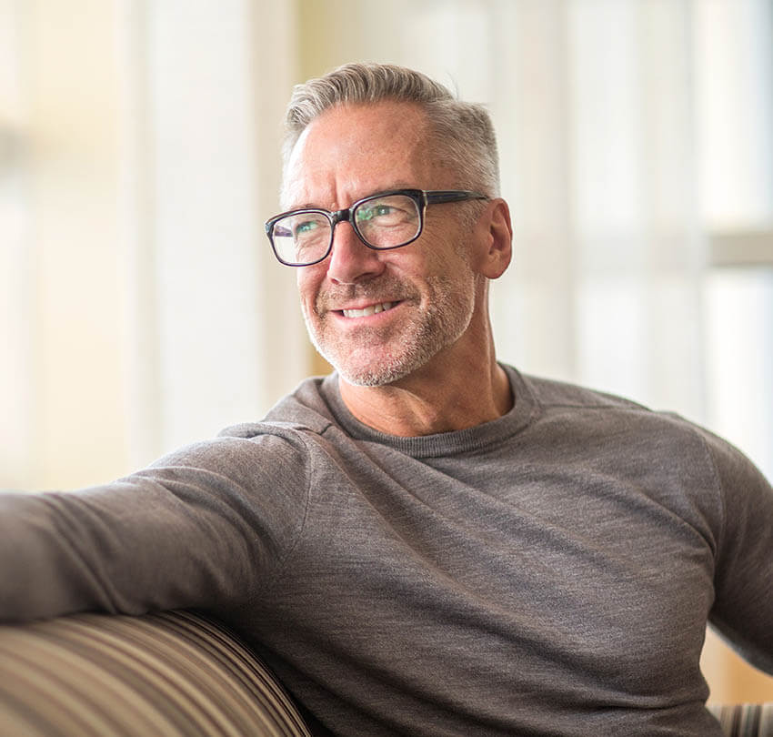 Smiling middle-aged man with glasses, showcasing confidence and vitality, representing the benefits of All-on-X dental implants for improved quality of life.