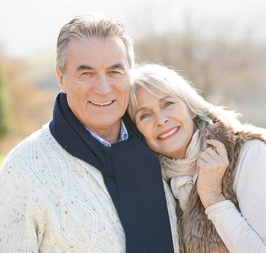 Elderly couple smiling warmly outdoors, representing comfort and care in modern dentistry at Biodental Health and Longevity in Pensacola.