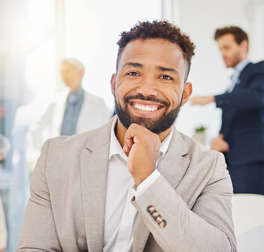Smiling man in a suit seated in a dental office, representing patient satisfaction and care at Biodental Health and Longevity, emphasizing urgent dental services and pain relief.