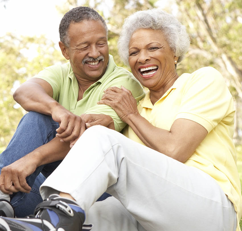 Happy older couple enjoying time together outdoors, smiling and laughing, representing the confidence and joy restored by modern dentures at Biodental Health and Longevity.