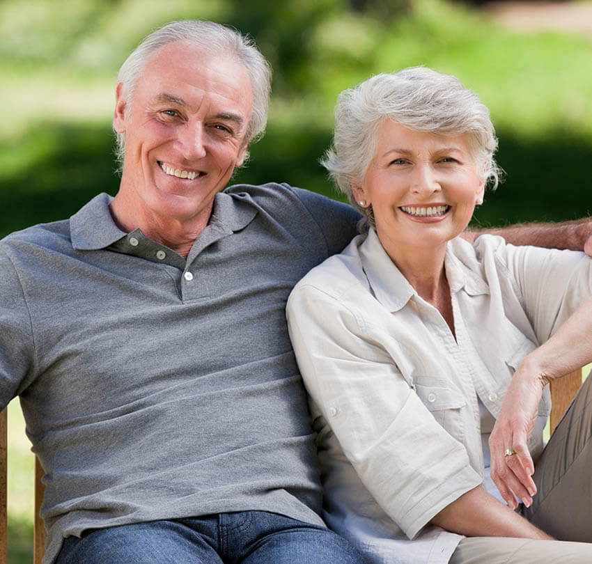Happy senior couple smiling together, showcasing their restored confidence and healthy smiles, relevant to full-mouth reconstruction services offered by Biodental Health and Longevity in Pensacola.