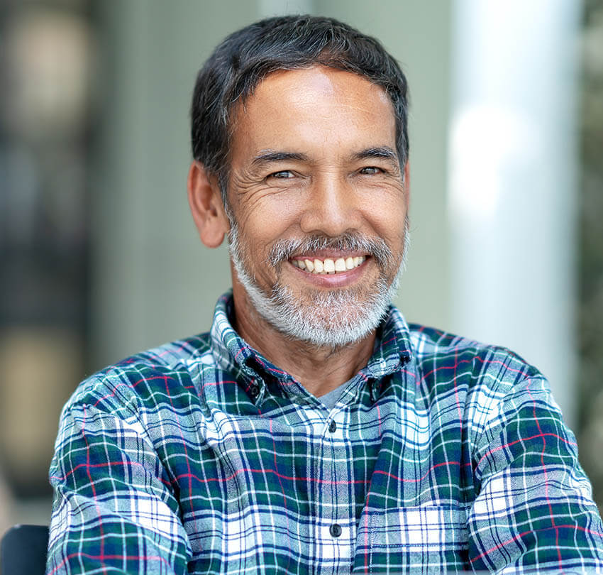 Smiling older man with a full set of teeth, showcasing confidence and a complete smile, representing the benefits of full-mouth reconstruction at Biodental Health and Longevity.