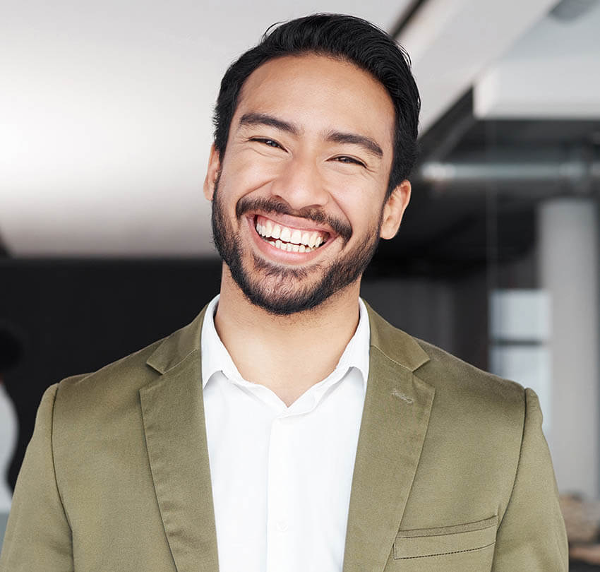 Smiling man in a suit showcasing a healthy smile, representing the benefits of custom mouthguards for dental protection and oral health.