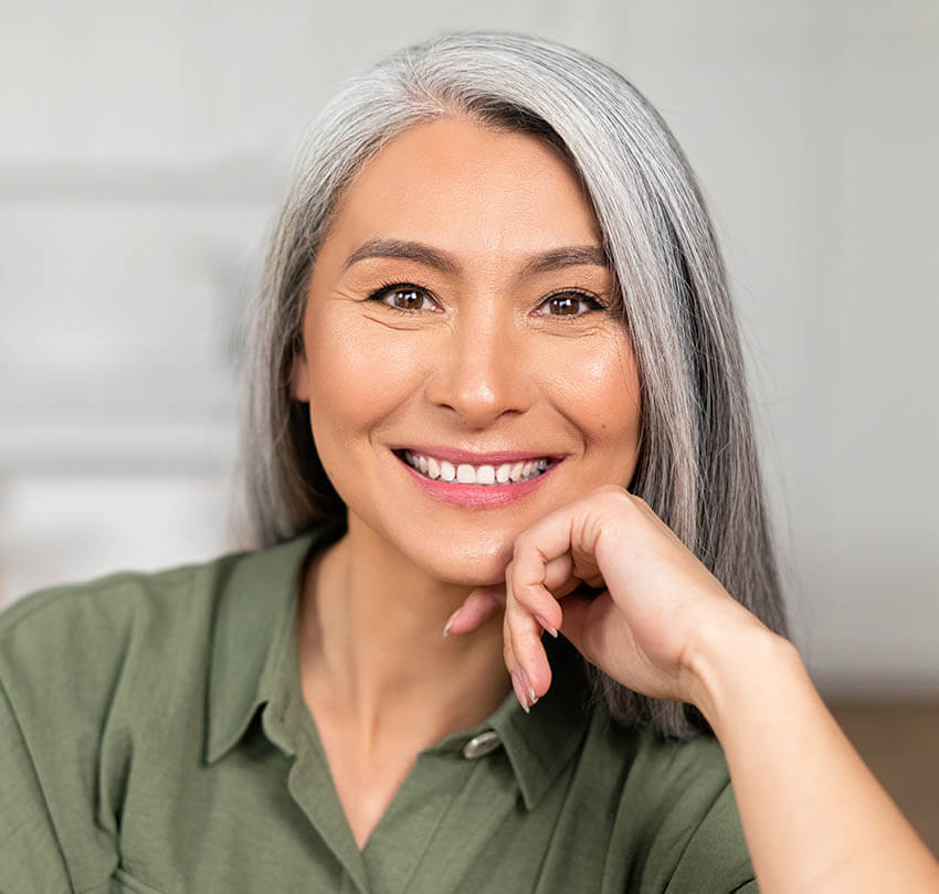 Smiling woman with gray hair showcasing a natural-looking smile, representing the benefits of same-day crowns at Biodental Health and Longevity in Pensacola.