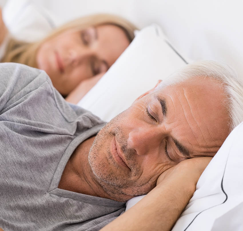 Couple sleeping peacefully in bed, representing improved sleep quality and restful nights associated with effective sleep apnea treatments.