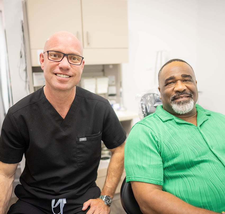 Dentist and patient smiling together in a dental office, showcasing a comfortable and friendly atmosphere for non-invasive dentistry in Pensacola.