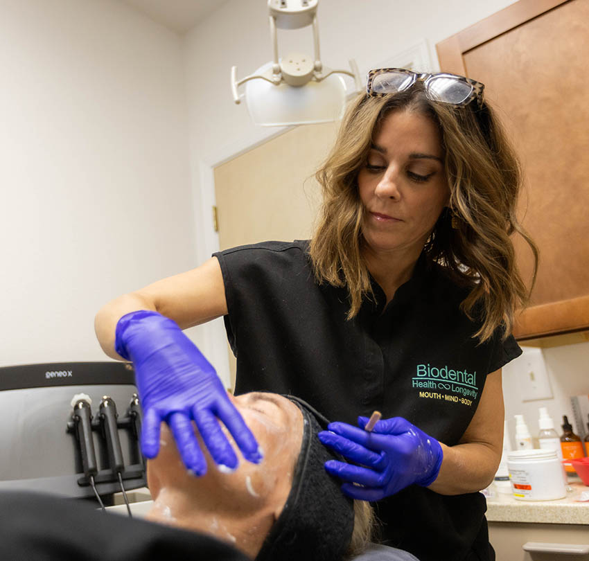 Dental professional at Biodental Health and Longevity providing facial treatment, showcasing advanced care in a modern dental office setting.